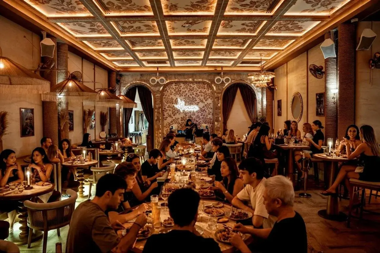 Guests dining inside Baia Bangkok under warm lighting and a patterned ceiling