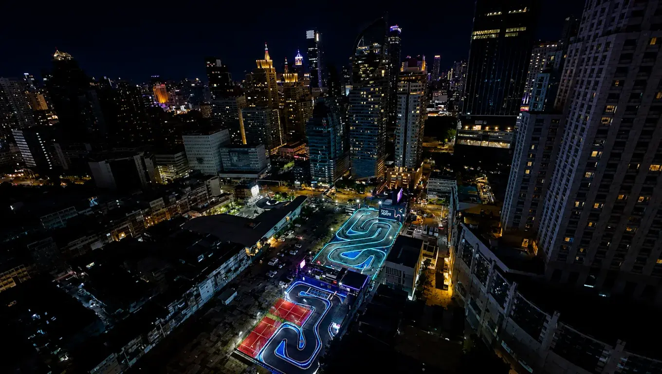Top Kart's illuminated track surrounded by Bangkok high-rise buildings at night